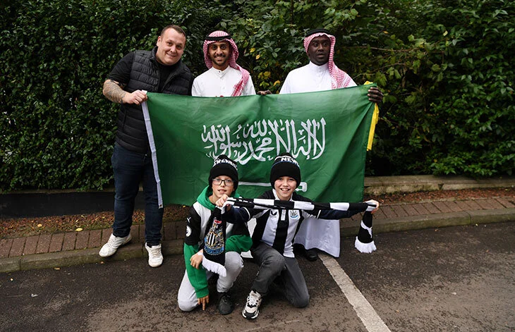 קבוצת אנשים מחזיקים דגל ירוק ועליו כיתוב בערבית