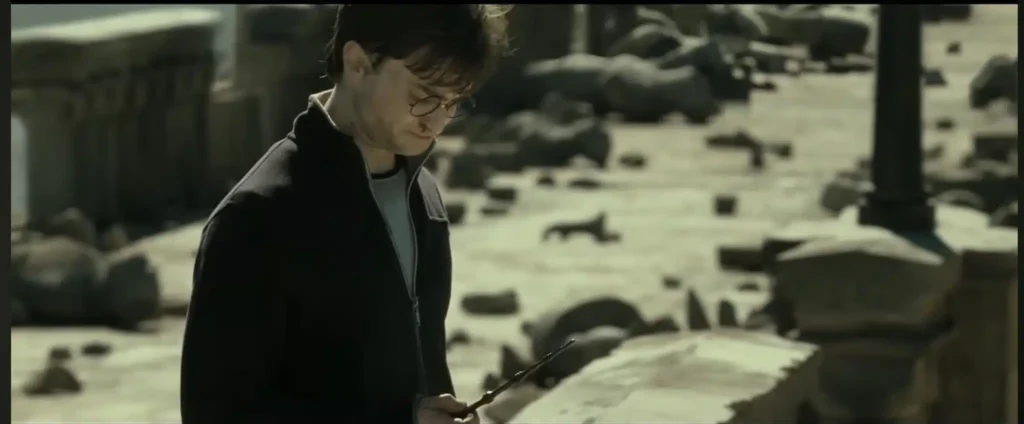 הארי פוטר ב״אוצרות המוות חלק 2״ עומד מחוץ להוגוורטס ומשמיד את שרביט הבכור (אולפני האחים וורנר).